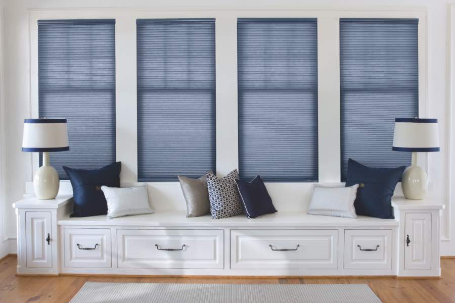 Blue cellular shades on four windows over a white window seat